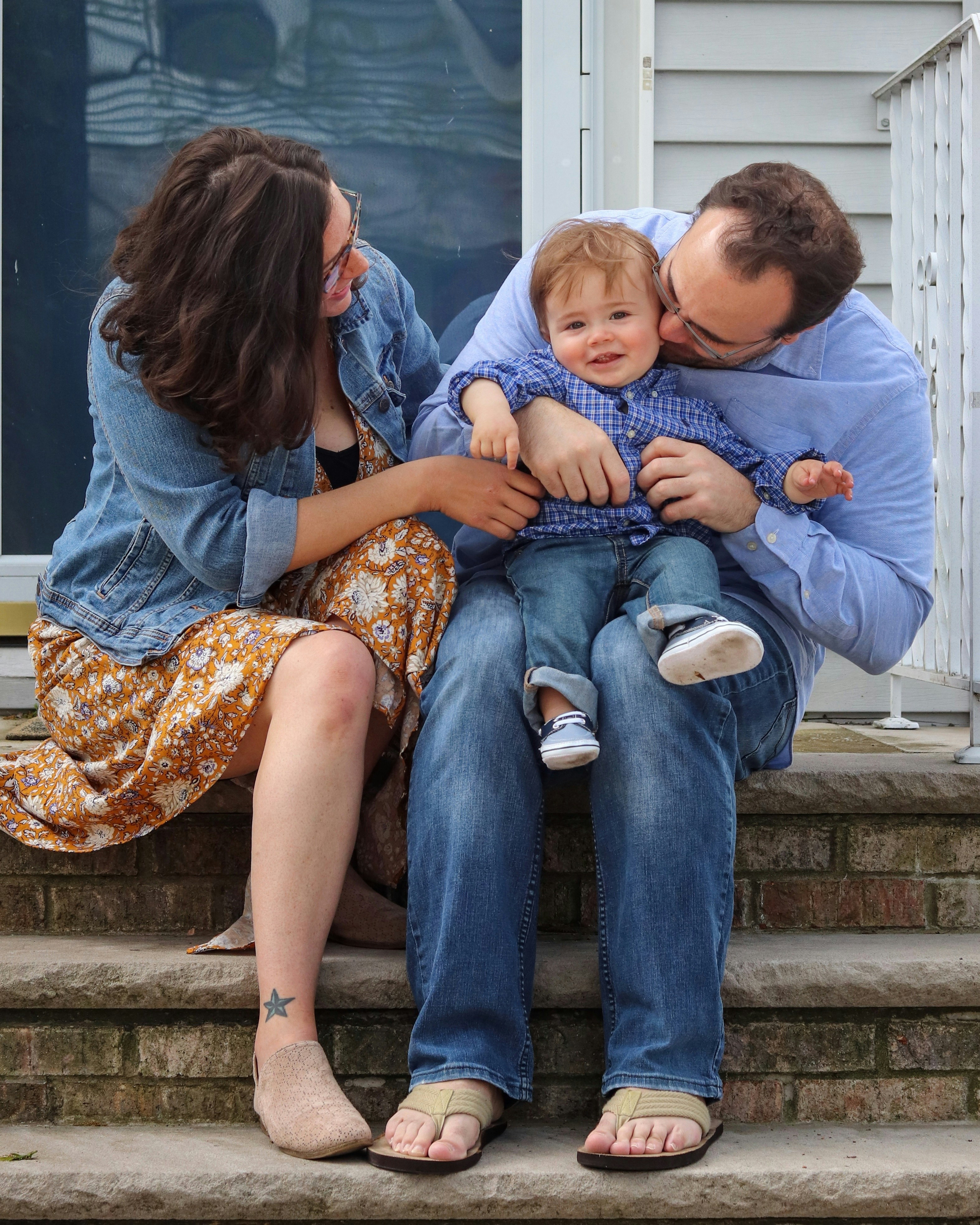 Family portrait: Parents with toddler son on steps, smiling.